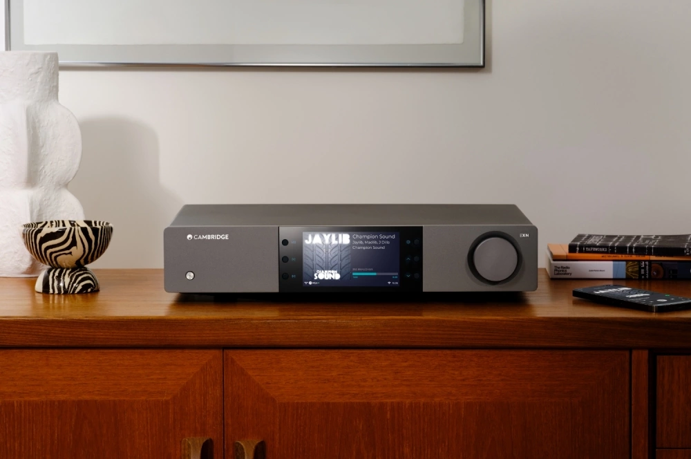 Hudební streamer Cambridge Audio zobrazený na dřevěné skříni